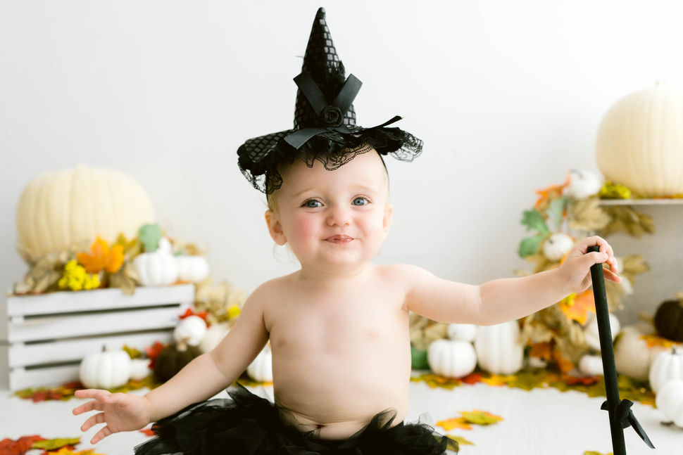 baby in witch costume pouting during autumn mini session