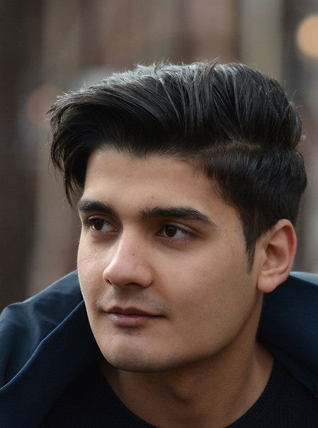 Portrait of a young man with a calm, reflective expression, representing a separated migrant child.