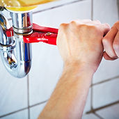 Pipe wrench under sink held by hands