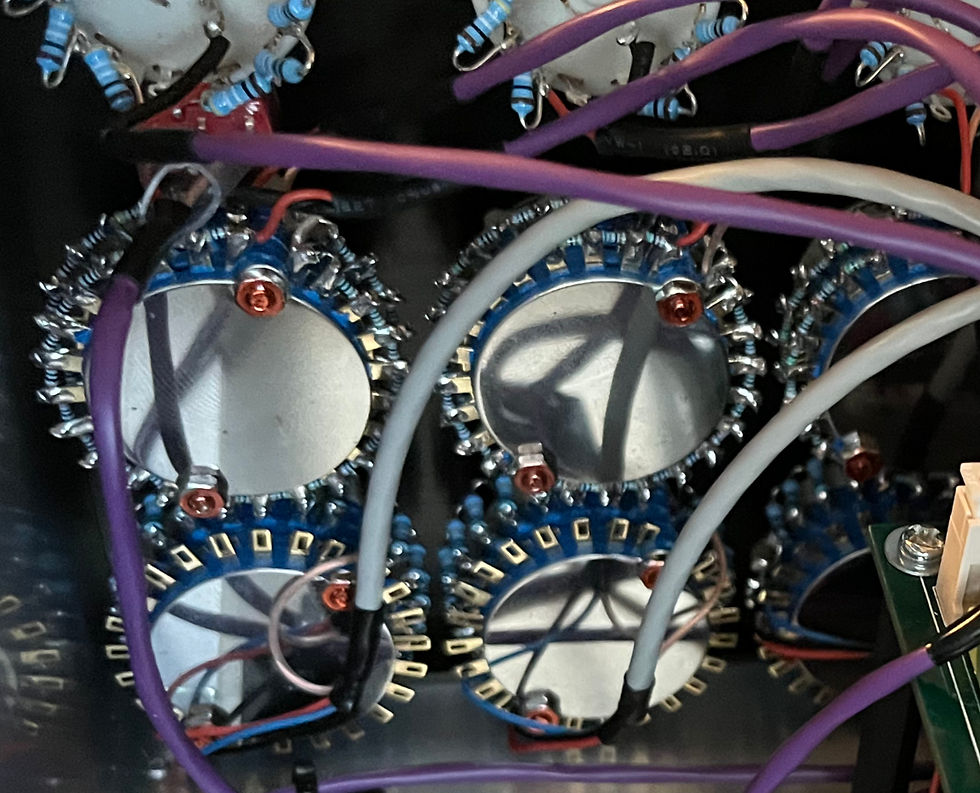 紫と白の配線が絡み合う複雑な電子回路。青い円形の部品が配置され、黒い背景が対比を成している。