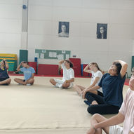Mixed group of teenage boys and girls doing seated neck side stretch in school gym — East West Yoga Teen Yoga Singapore ages 13 to 18