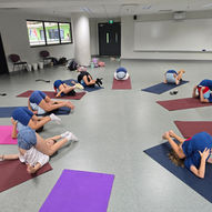 Pre-teen students doing playful happy baby pose on colorful yoga mats in school — East West Yoga Singapore ages 9 to 12