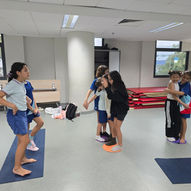 Pre-teen students doing partner balance board activity together during yoga class — East West Yoga Singapore school ages 9 to 12