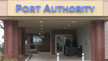 Port Authority building entrance with two people at the door, brick columns, and blue sign overhead