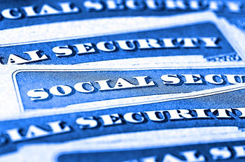 Close-up of blue Social Security cards stacked diagonally, showing bold white text and a security-document pattern.
