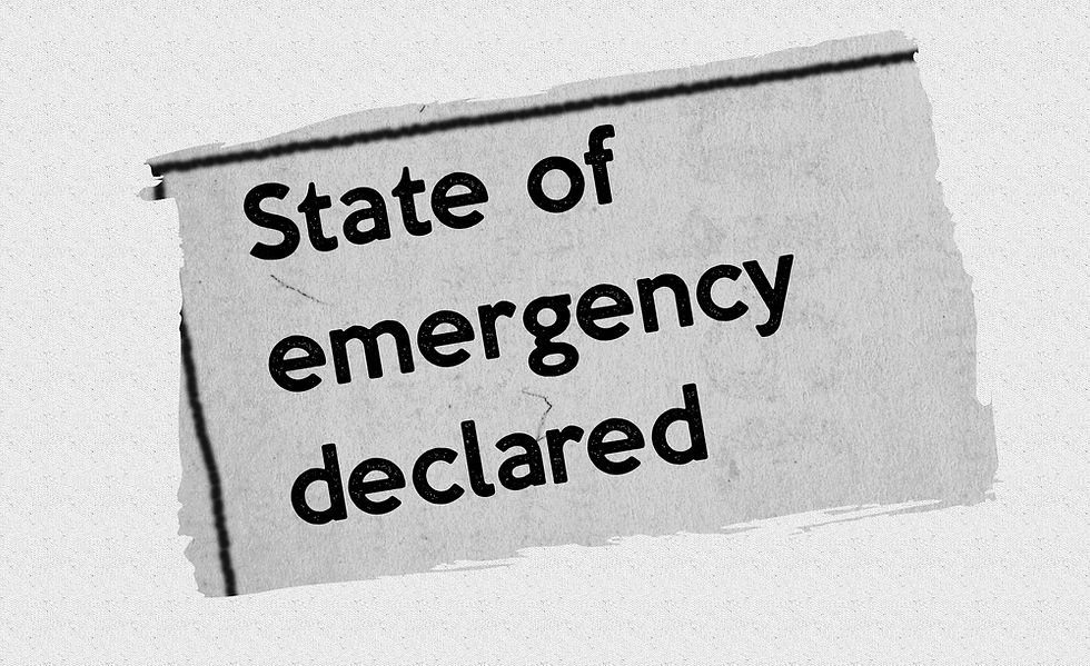 Torn paper sign in black-and-white reads State of emergency declared, suggesting urgent crisis or alert.