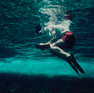 A snorkel diver is writing down detailed notes on his plastic writing pad after making measurements and drawings of the block-fort tower near the harbour entrance.