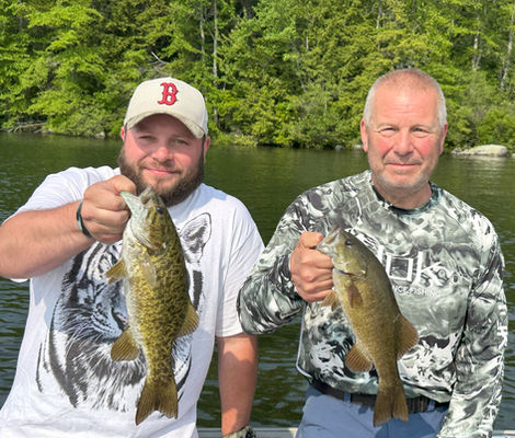 Father and son holding up smallmouth bass caught on Squam Lake in New Hampshire.