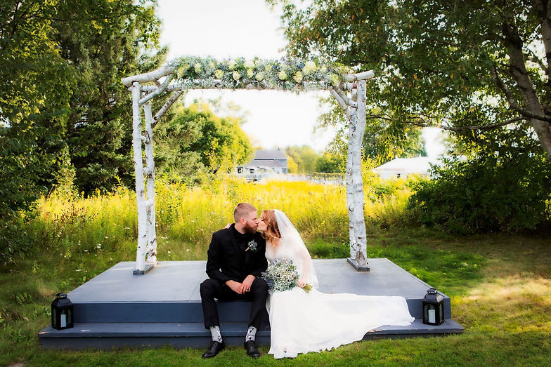 Bride and groom sharing a quiet moment beneath a birch arbor during an outdoor wedding ceremony in Kawartha Lakes