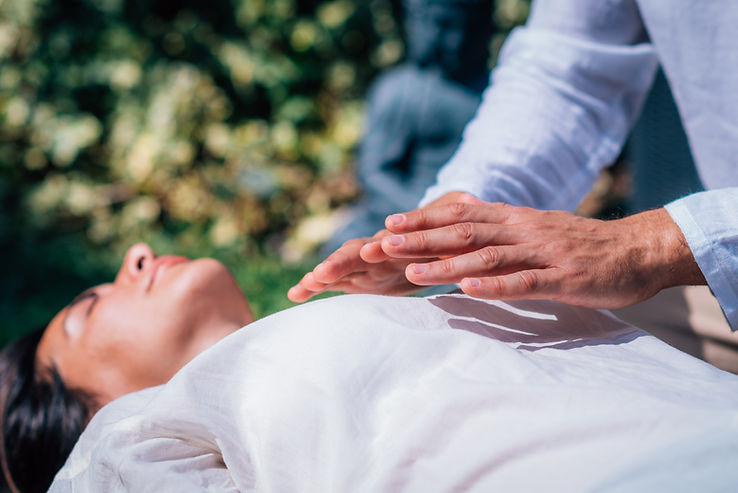 Woman in Reiki spiritual healing session Reiki therapist holding hands above heart chakra