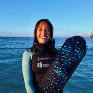 Woman holding long fins in a custom freediving wetsuit on a beach in Hawaii