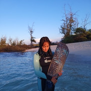 Woman holding long fins in a custom freediving wetsuit on a beach in Hawaii