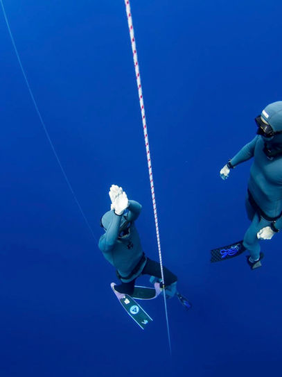 Diver ascends from the depths with a safety nearby