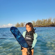 Woman holding long fins in a custom freediving wetsuit on a beach in Hawaii