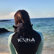 Woman holding long fins in a custom freediving wetsuit on a beach in Hawaii