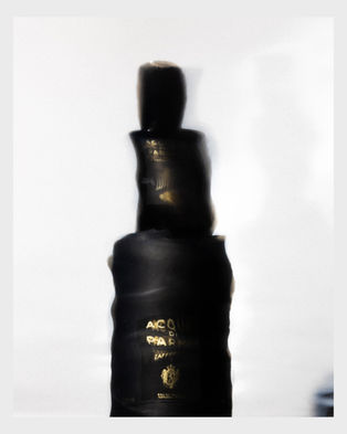 Fotografia artistica di una bottiglia di profumo Acqua di Parma Zafferano con effetto di movimento e luce morbida, scatto creativo di fotografo professionista di prodotti di lusso.