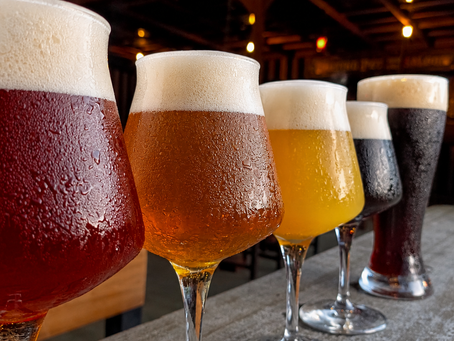 Five frosty craft beers in Ubud, tulip glasses—red, amber, gold and dark—lined on a rustic bar in a dim, warm-lit brewery.