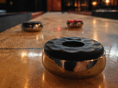 Close-up of shuffleboard pucks on the table at The Melting Pot Saloon in Ubud, Bali.
