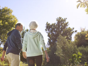 Two older adults walking in a park