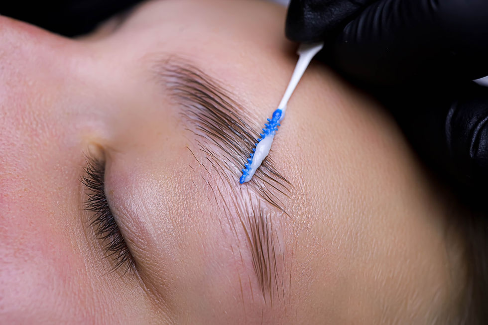 Kosmetikerin trägt Pflegeprodukt mit Bürstchen auf Augenbrauen während Brow Lifting auf
