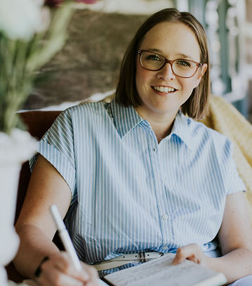 Theresa Smith smiling at the camera while writing in a notebook in a professional setting.
