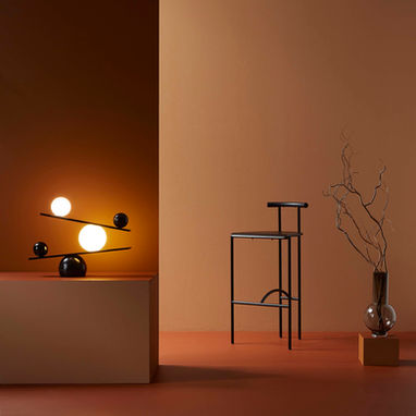 A minimalist room in three tonal shades of brown with a contemporary lamp, chair and vase