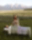 Annelies holding an owl wing while giving a shamanic energy healing to a woman on a table in a meadow near mountains