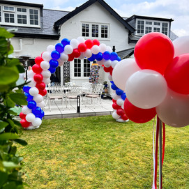 Spiral balloon arch in the garden for corporate events. Balloon arch was assembled by Confetti Party, balloon company in Guildford
