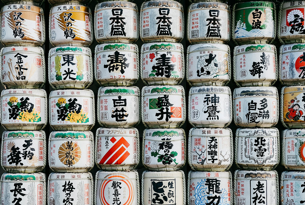 Stacked sake barrels with colorful Japanese calligraphy and illustrations. Rows of barrels create a vibrant, traditional pattern.