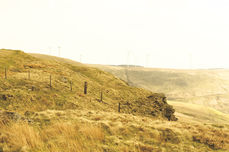 Mountain top with yellowed grass with another mountain valley seen in distance.
