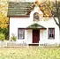 White cottage with green roof and red trim, surrounded by autumn trees and a white picket fence. Bright and cheerful fall scene.