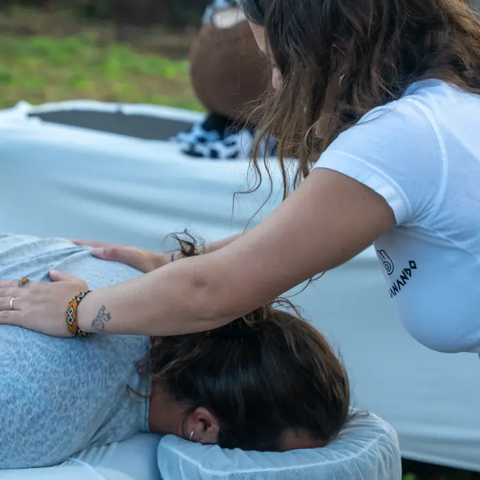 אישה נותנת עיסוי ללקוחה, על שולחן עיסוי בחוץ