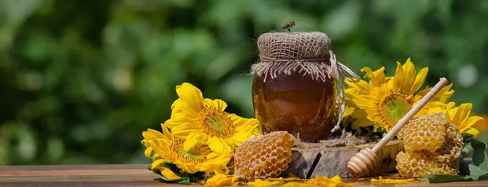 A jar of honey on a table surrounded by flowers and honeycomb