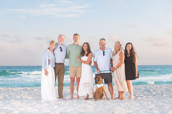 A large family with a dog posing on a beach in Seaside, FL