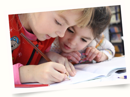 Two little girls writing on a book