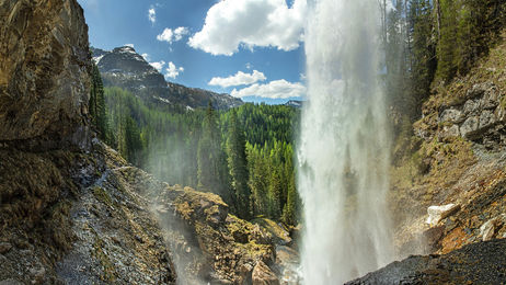 Wasserfall von hinten fotografiert mit Blick auf die Berg- und Waldlandschaft von Obertauern