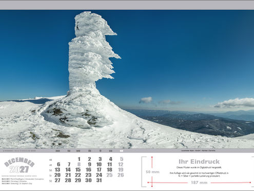 "Kalenderblatt Dezember 2027 mit einem von Wind und Schnee vereisten Denkmal in den Lavanttaler Alpen, im Hintergrund die Weinebene mit großen Windrädern unter klarem blauen Himmel.