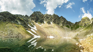 Schneereste spiegeln sich im Gefrorenen See in den Triebener Tauern
