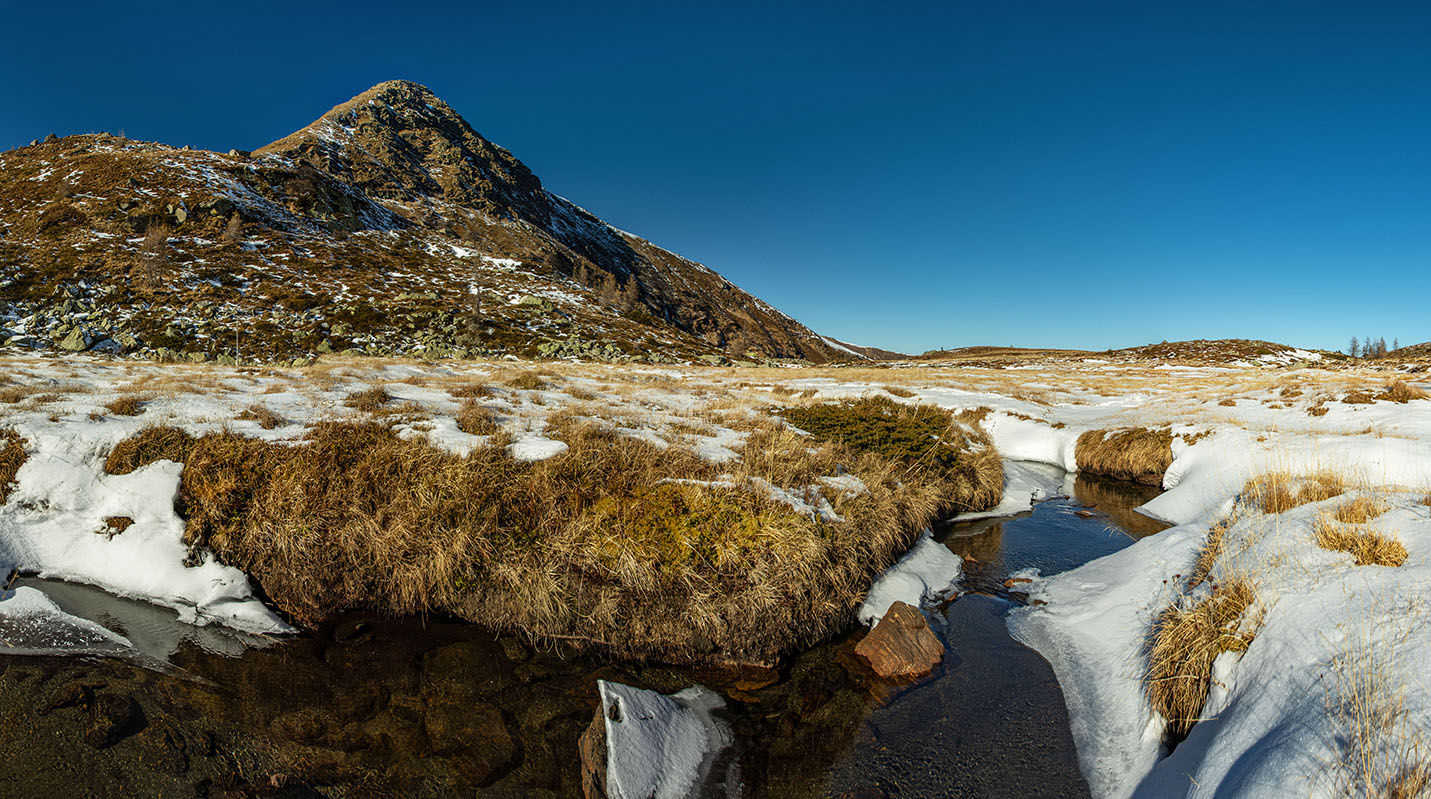 Erstarrte Hochebne mit dünner Schneedecke in Ocker- und Brauntönen