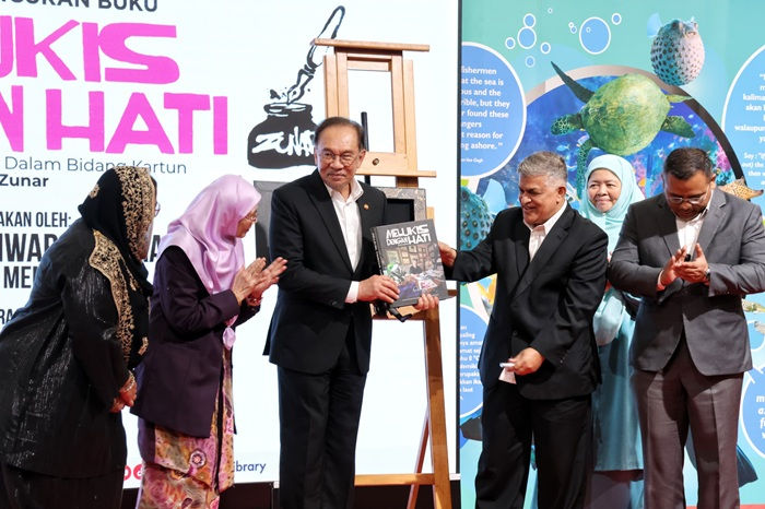 Zunar (di sebelah PM) memegang buku ''Melukis Dengan Hati'' dokumentasi perjalanan seni selama 50 tahun