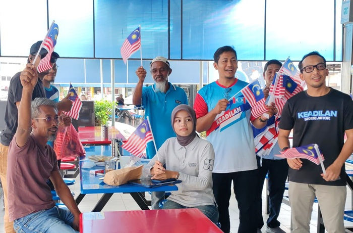 Md Ysahrudin (dua dari kanan) dan Fakharuddin (kanan sekali) mengagih bendera di medan selera