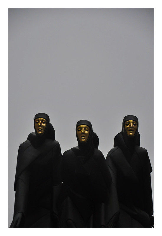 Three abstract figures in black robes and golden masks stand against a gray background, creating a mysterious, solemn atmosphere.
National Drama Theatre, Vilnius