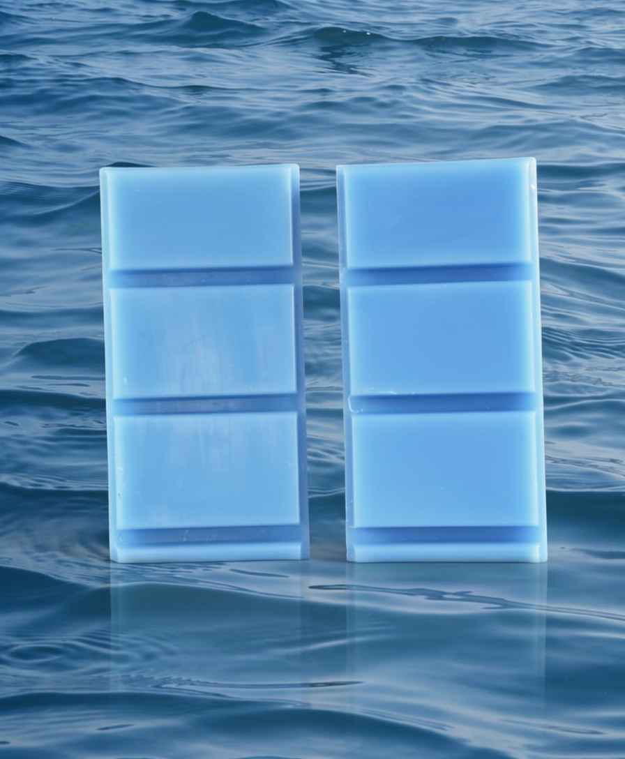 Two light blue wax melts floating in water