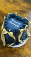 Navy blue cake with gold ribbons and "Sweet 16 Madagaska" on top.