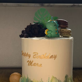 White cake with Happy Birthday Mara text and green decorations, delicious flavors