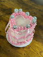 Heart-shaped cake with pink frosting, disco balls, and ribbon decoration on table