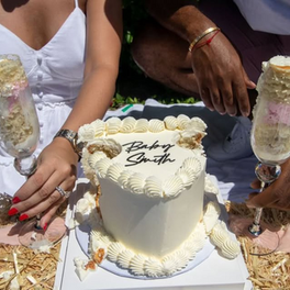 Couple with cake that says Baby Smith, celebrating a gender reveal party.