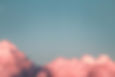 Aerial picture of blue sky with pink-hued clouds.
