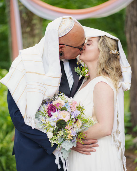 Bride and groom kissing during ceremony with traditional garments.
