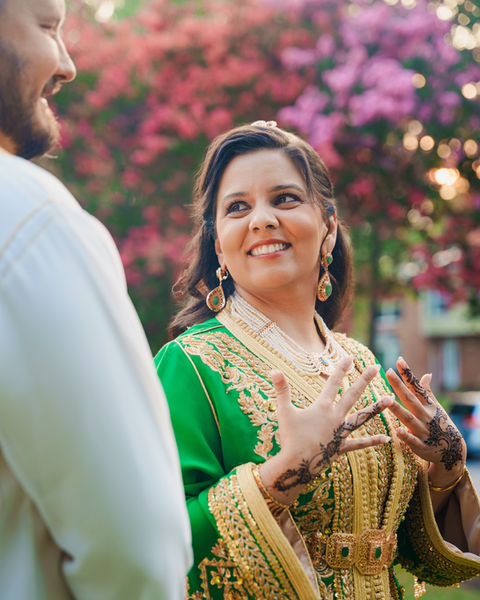 Woman in green traditional outfit smiling during wedding celebration.